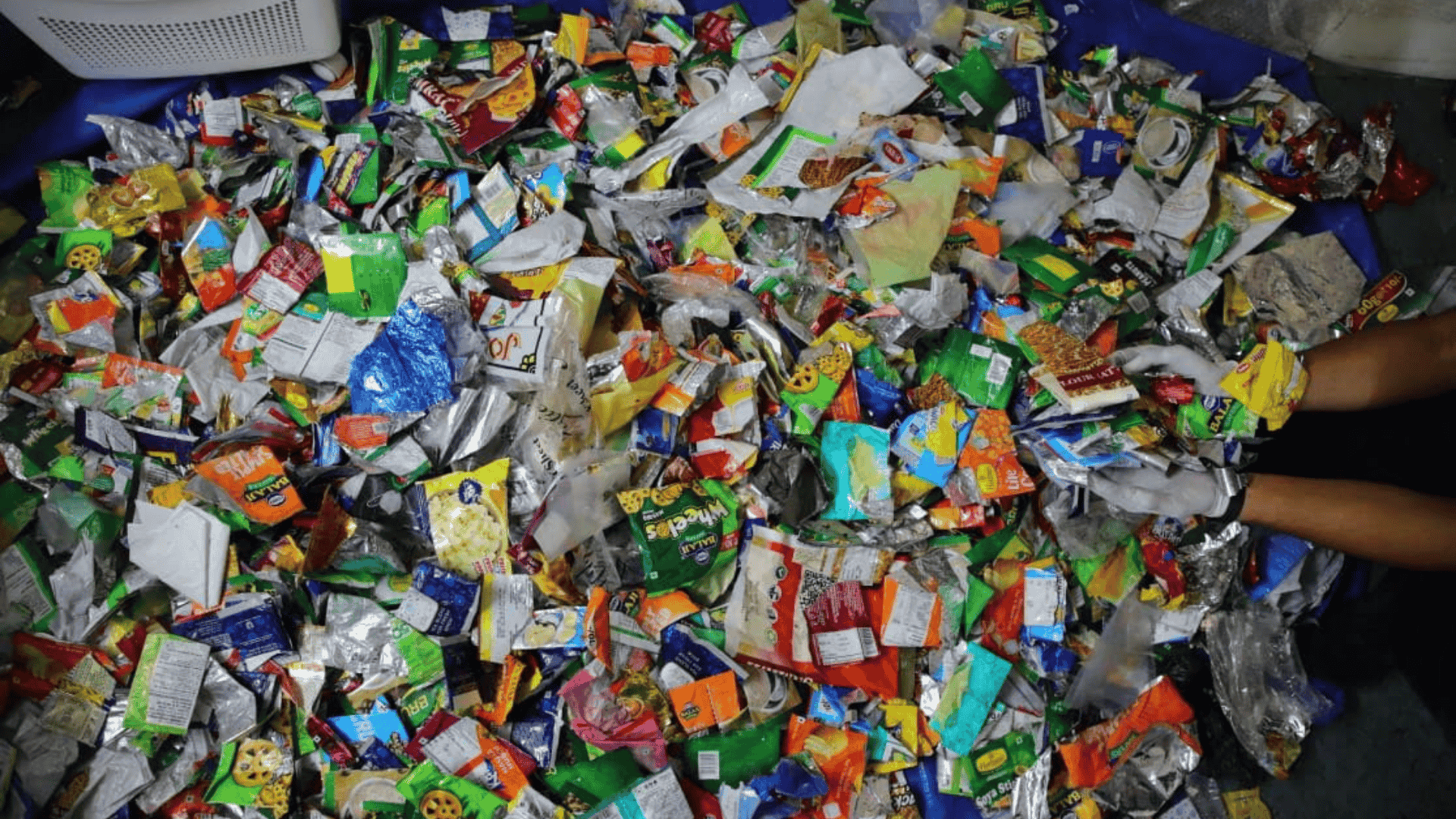 A large heap of discarded MLP plastic wrappers, the raw material Without by Ashaya transforms into recycled sunglasses through its Scale-Up supported solution.
