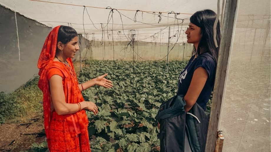 Saumya speaking with a woman farmer inside a Kheyti shade net house.