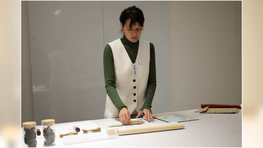 Neha Jain examining sustainable packaging prototypes and raw seaweed samples at a table.