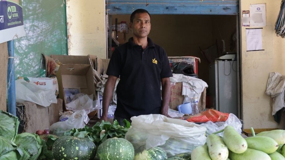 A vegetable shopkeeper stands behind fresh produce at his shop in Uttar Pradesh.